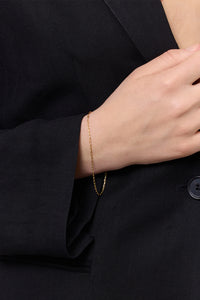 Woman in a  black blazer wearing a gold plated chain bracelet from Carré.