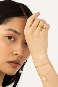 Woman wearing gold plated jewellery from Carré. The bracelets are the wave bracelet and the figaro bracelet.