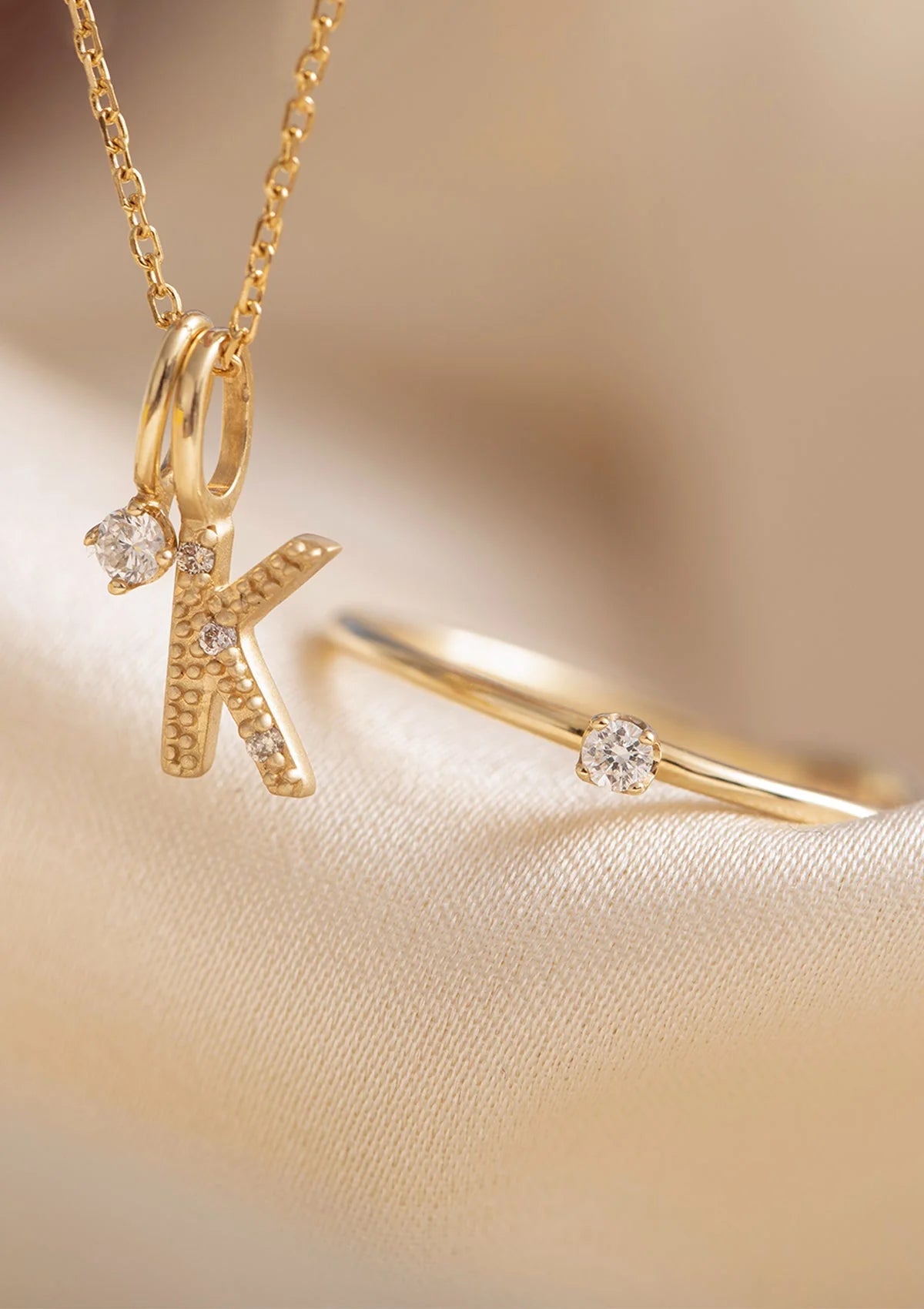 10k solid gold jewellery set with diamonds from Carré. There's a letter pendant with diamonds with the letter K, a diamond pendant and a diamond engagement ring.