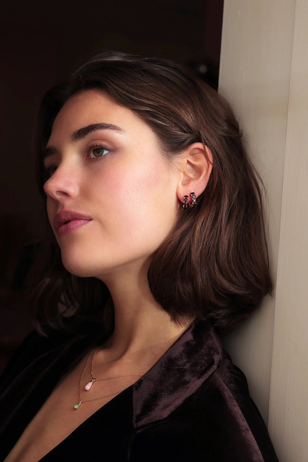 Smiling woman wearing gold plated sterling silver jewellery from Carré. The long earrings are set with January's birthstone garnet. The ear stud is also set with a red garnet gemstone.