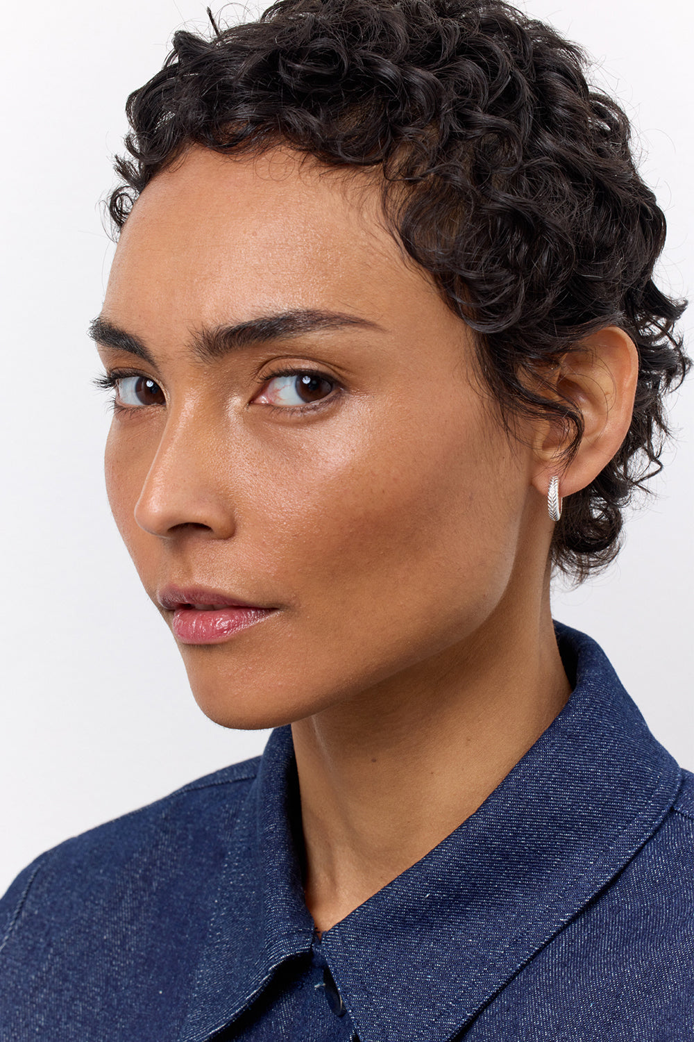 Woman wearing sterling silver hoops from Carré in a thick style and with a fishbone pattern