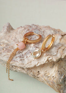Two gold plated hoops from Carré in creole style set with charms. The charms have a pink opal gemstone, a chain charm, and a prasiolite charm.