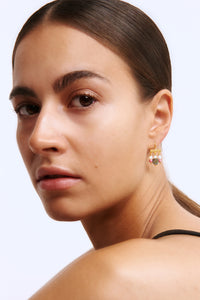 A woman wearing a long gold plated earring from Carré. The earring is plated in 18k gold and set with Pearls, labradorite and tourmalines