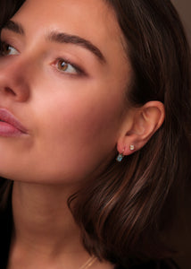 Woman wearing gold plated long earrings from Carré. The long earrings have a chain and are set with three labradorite gemstones