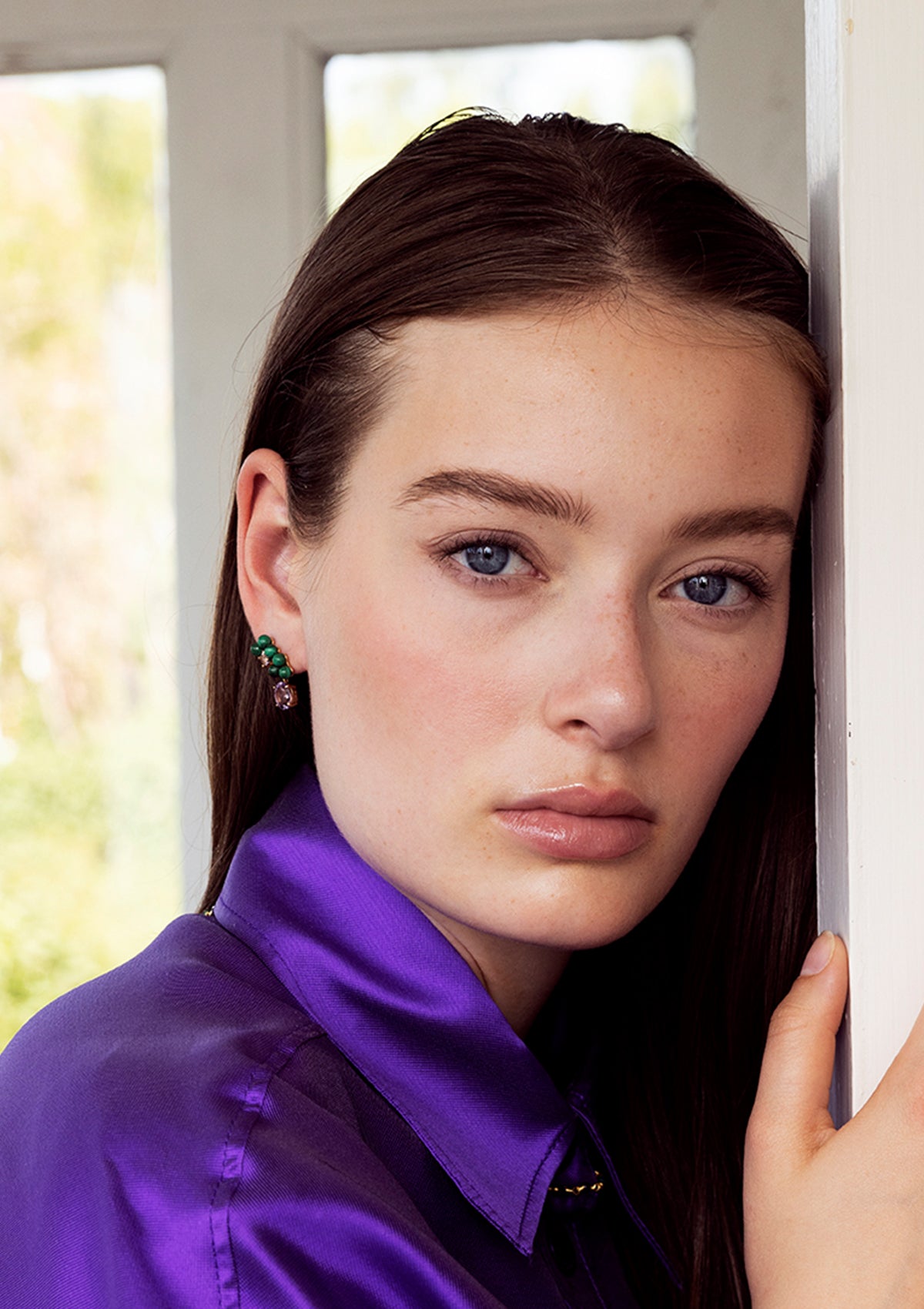 Woman in a purple shirt wearing malachite and amethyst jewellery from Carré