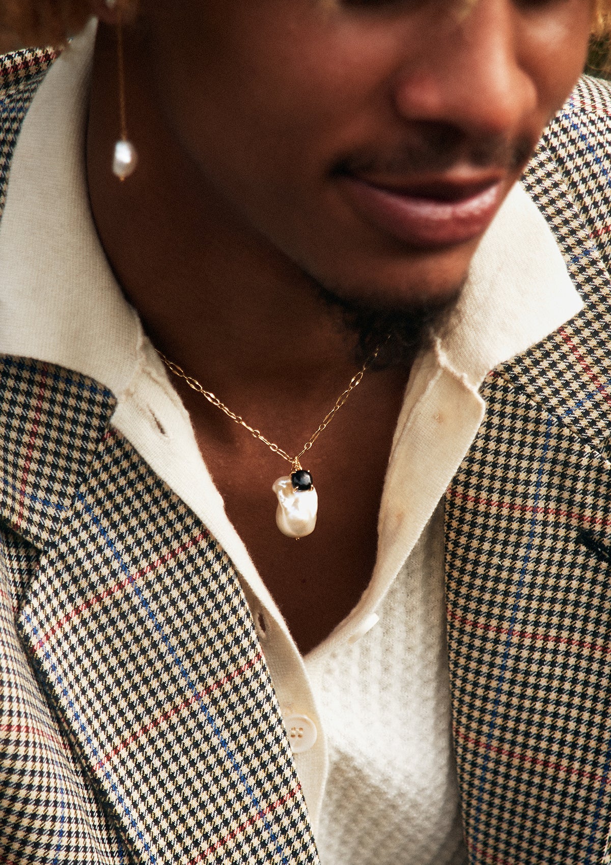 Young man wearing gold plated Black Agate jewellery from Carré. The pendant is made in black agate, and the other pendant is a large freshwater pearl pendant. 
