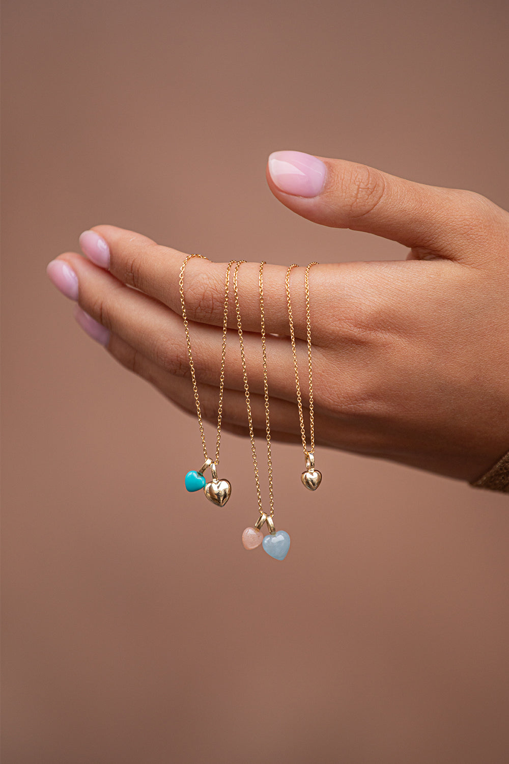 Woman holding pendants for necklaces with heart shaped gemstones and diamonds for valentines day