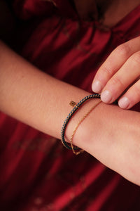 Woman with bracelets from Carré in 9 karat gold and a braided nylon bracelet in True Blue. Carré Jewellery Copenhagen.