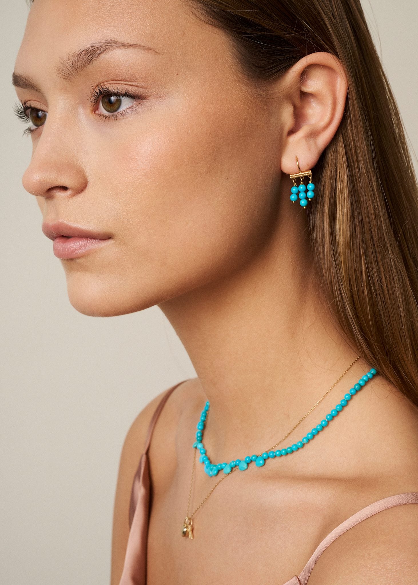 Ung kvinde med øreringe og halskæde i guldbelagt sterling sølv fra carré jewellery med turkis ædelsten