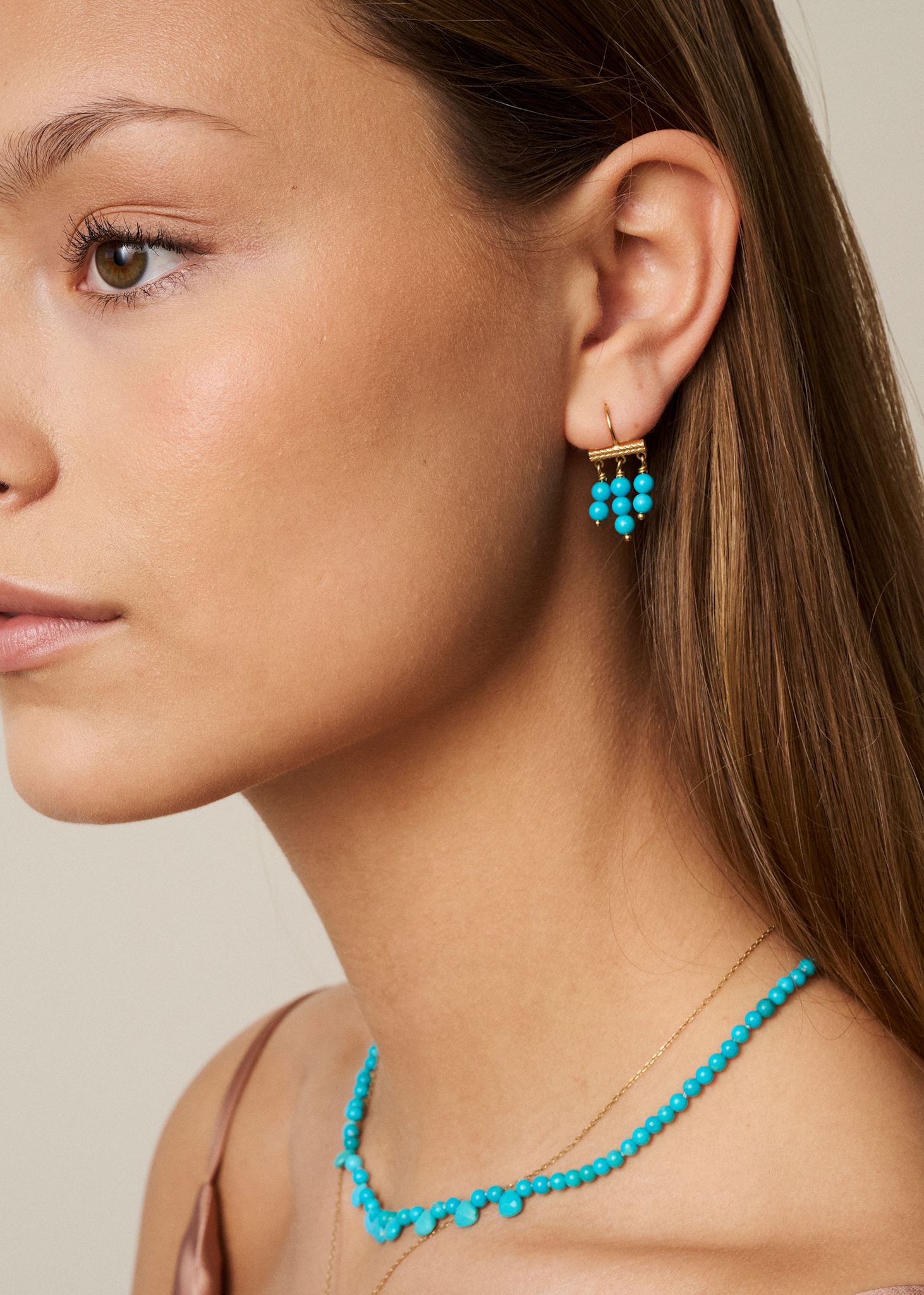 Ung kvinde med store hængeøreringe fra carré med tre rækker af blå turkis ædelsten i guldbelagt sterling sølv 
