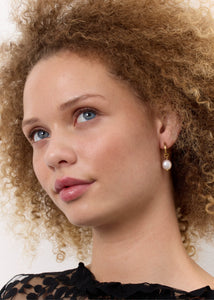 Woman wearing a gold plated sterling silver hoop with a baroque freshwater pearl charm