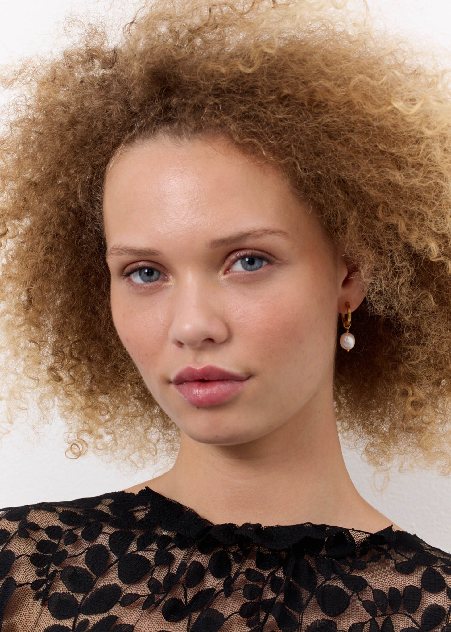 Woman wearing a gold plated sterling silver hoop with a baroque freshwater pearl charm