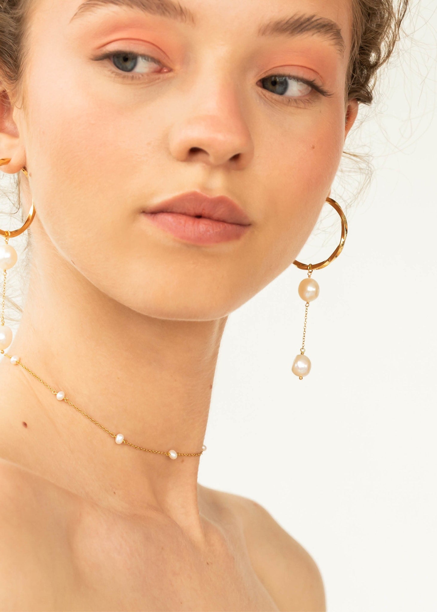 Woman wearing bibi charm from carré jewellery in gold with two white freshwater pearls