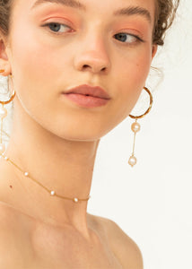 Woman wearing bibi charm from carré jewellery in gold with two white freshwater pearls