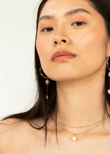 Woman with large hoop earrings and a freshwater pearl charms from carré jewellery