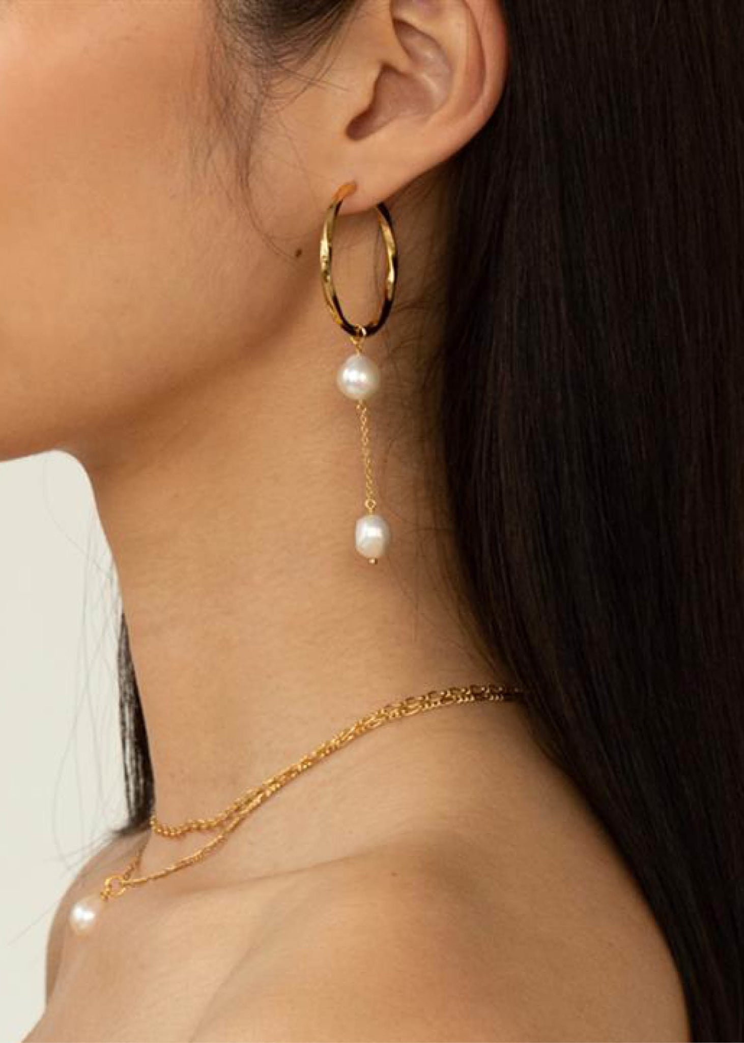 Woman with large hoop earring with a ong pearl charm with two freshwater pearls