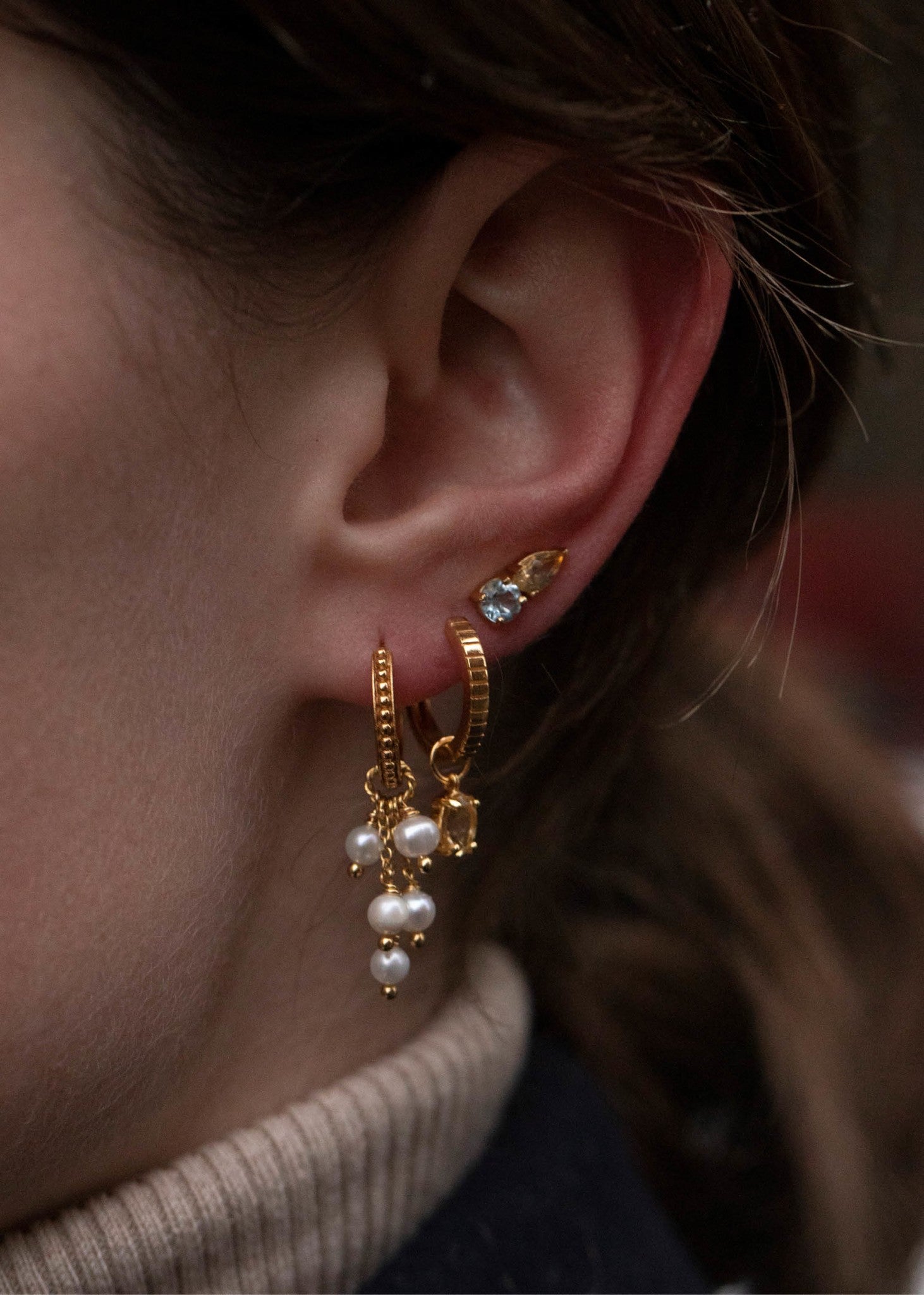 Woman wearing dangling gold earrings with freshwater pearls from Carré Jewellery