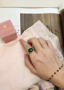 Woman wearing a large vintage gold plated silver ring with lace edges and a large green agate gemstone