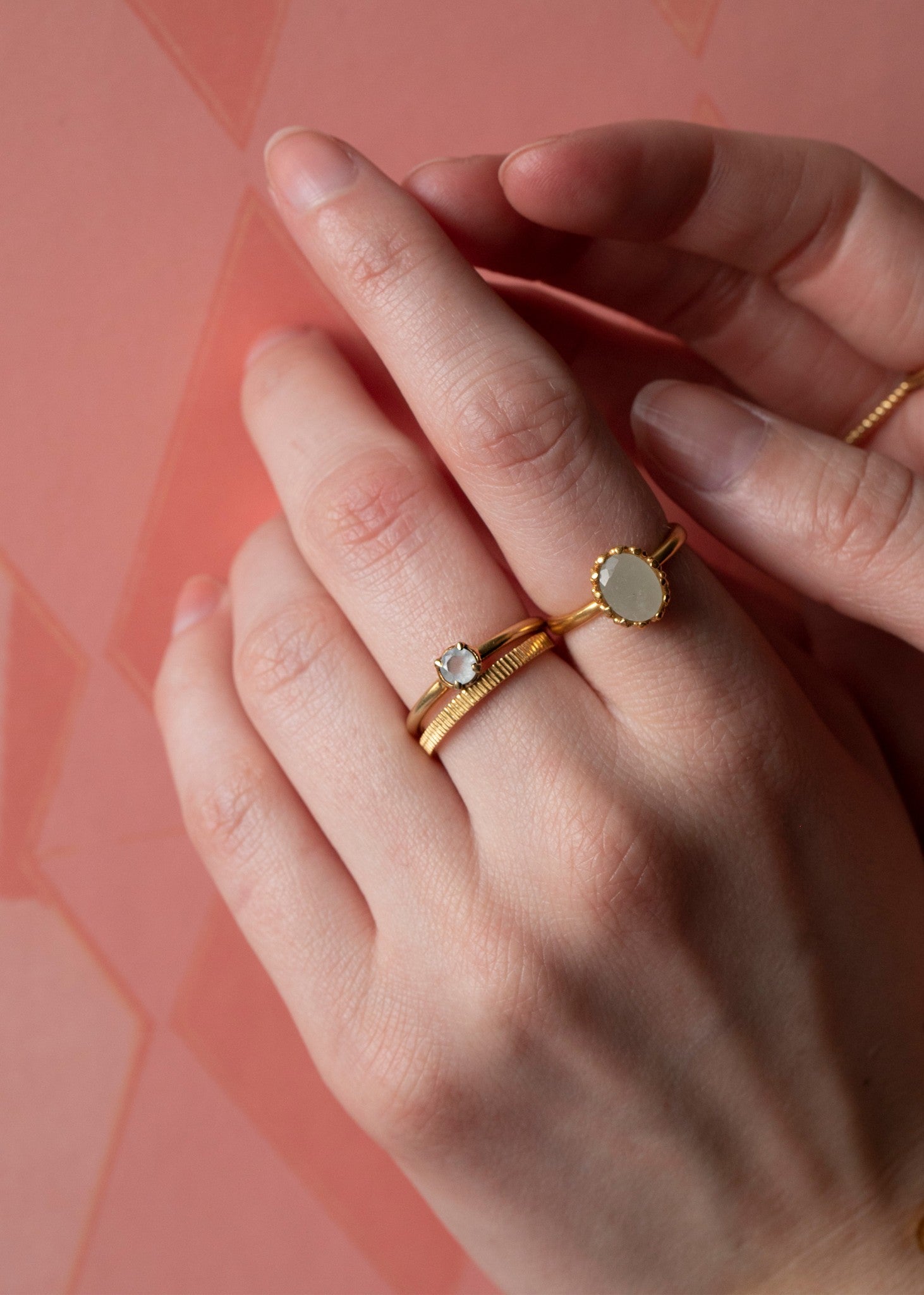 Woman wearing two gold birthstone rings for march set with blue Aquamarine gemstones in facet-cuts 