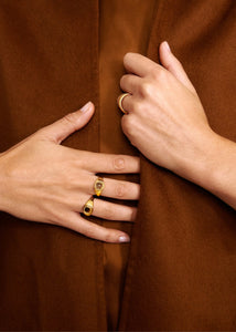 Woman in orange wearing gold plated sterling silver signét rings with stones from Carré Jewellery's Mirage collection