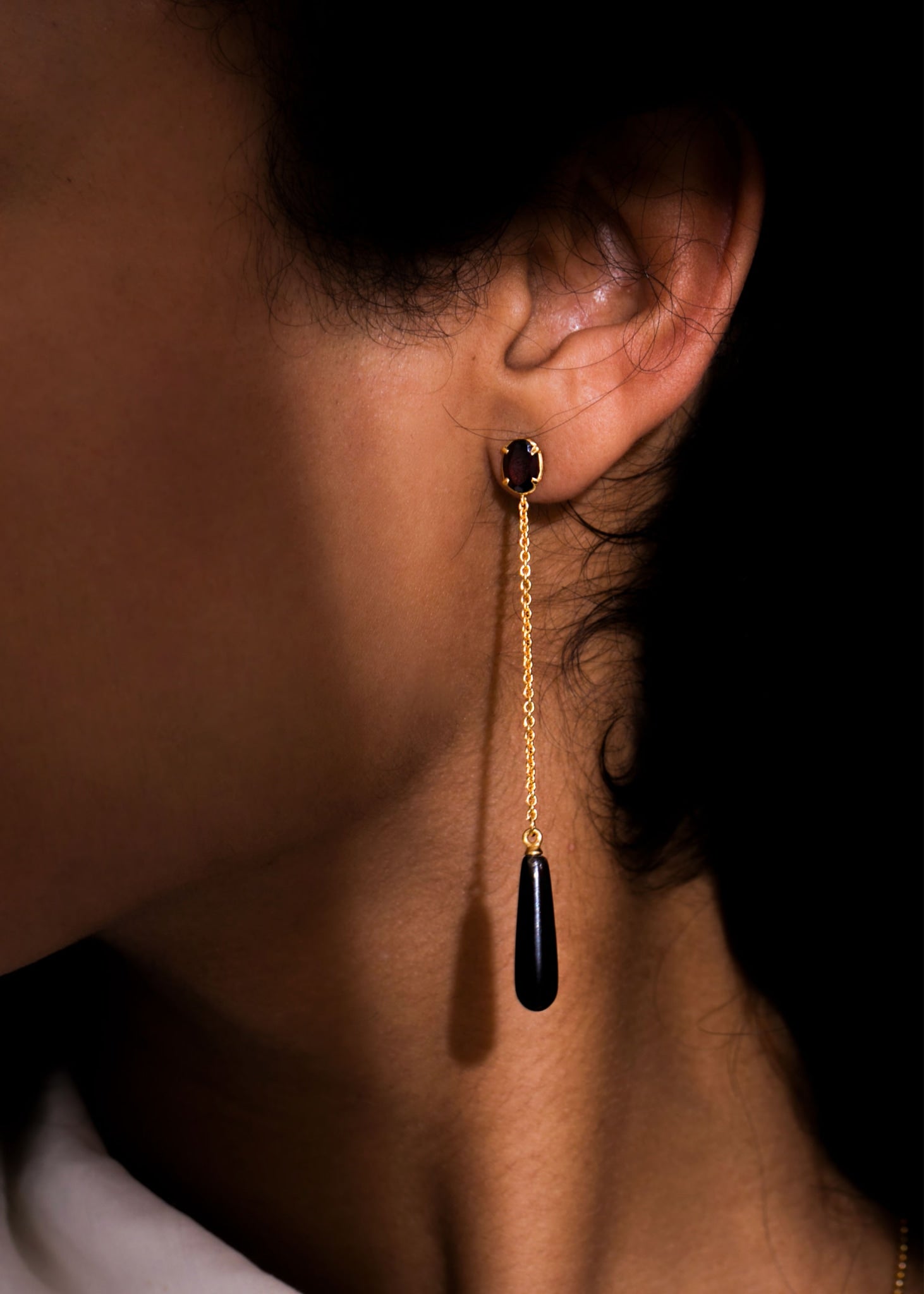 Woman with long earrings with a chain and a drop of Brown Quartz and a facet-cut Red Garnet gemstone