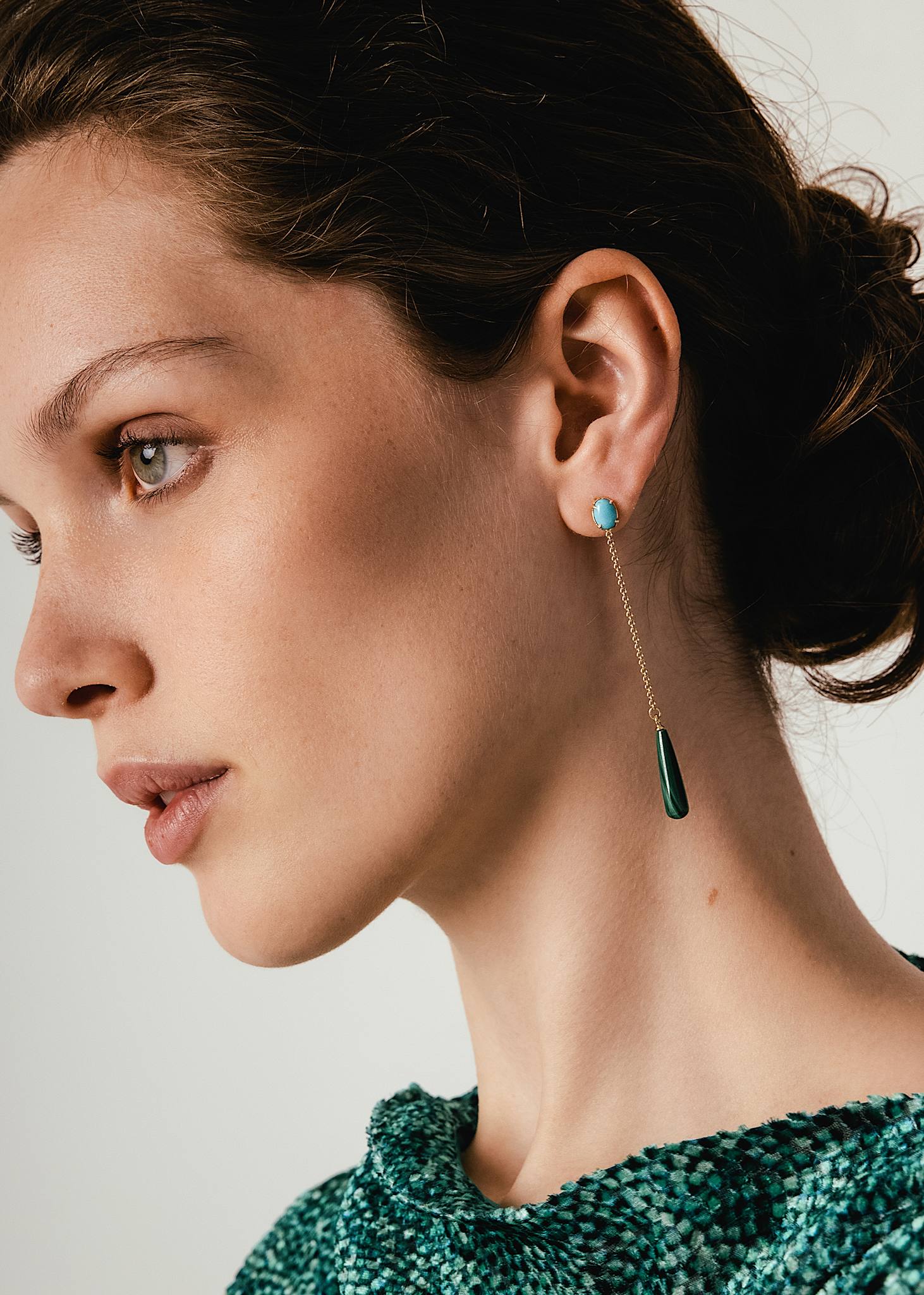 Ung kvinde med lange hængeøreringe fra carré jewellery med blå turkis ædelsten og lange kæder med grønne dråber af malakit ædelsten i bunden 