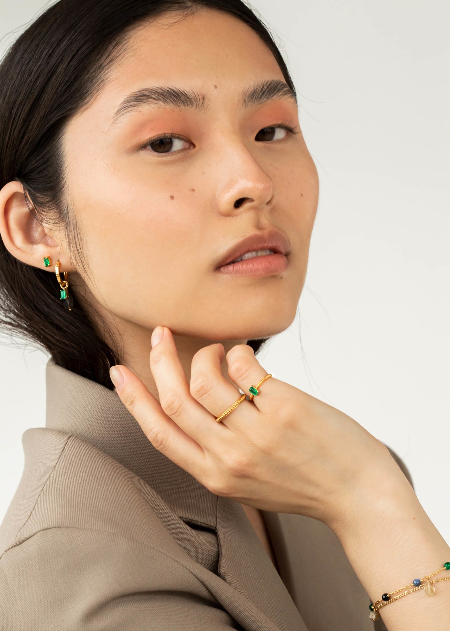 Kvinde med smykker i guld med grønne sten på udsalg hos Carré Jewellery 