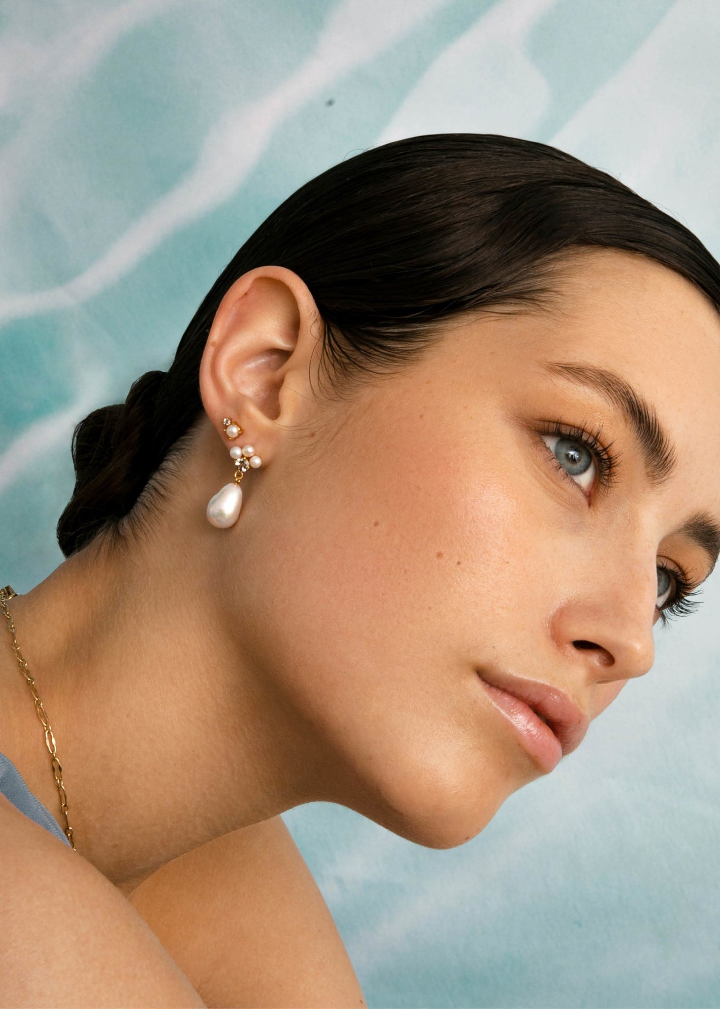 Woman wearing long pearl earrings and small pearl ear stickers from carré jewellery set with freshwater pearls, blue topaz and prasiolite gemstones