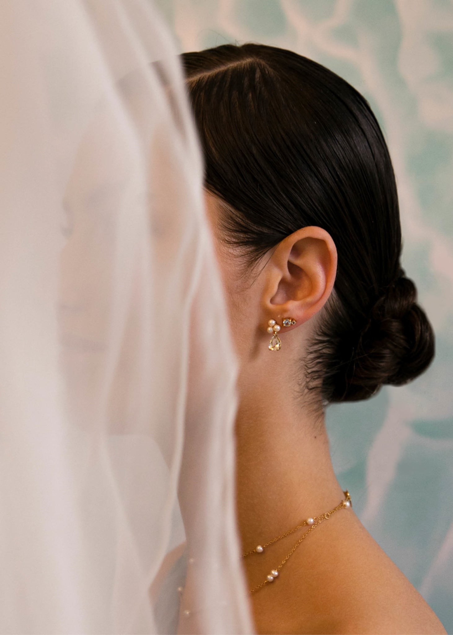 Bride wearing bridal ear studs in gold with freshwater pearls and blue topaz from carré jewellery