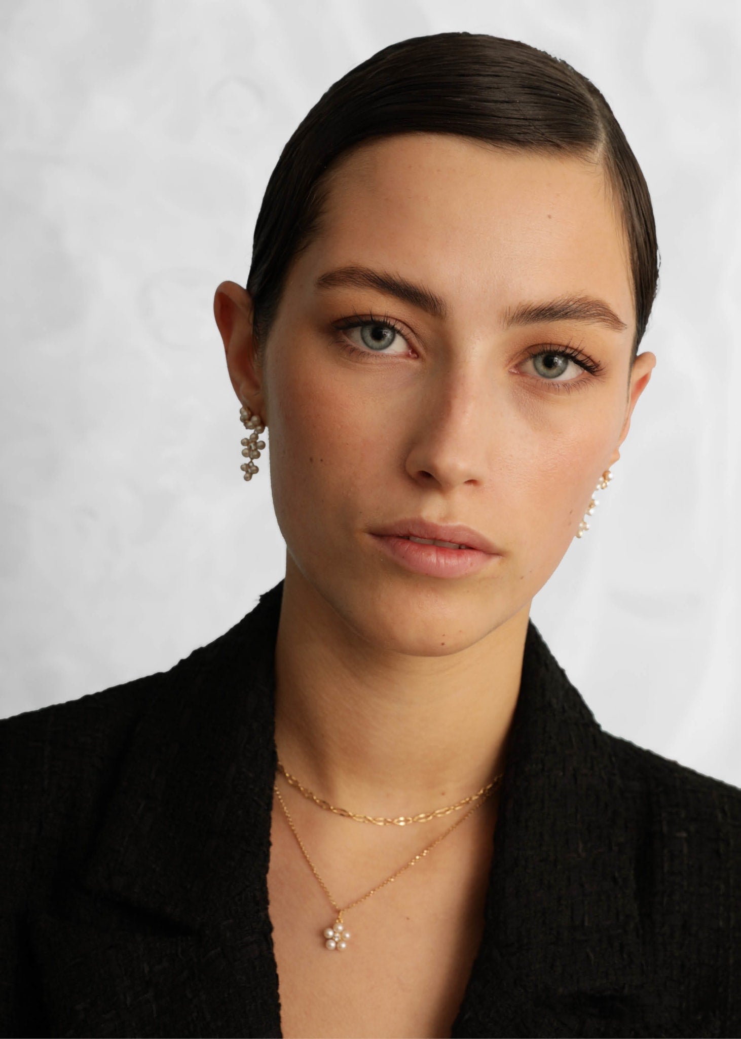 Woman wearing long dangling pearl earrings from carré jewellery in a flower shape with white freshwater pearls in gold plated sterling silver