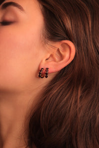 woman with two large hoops set with facet-cut red garnet gemstones in the hoop earring with creole closure