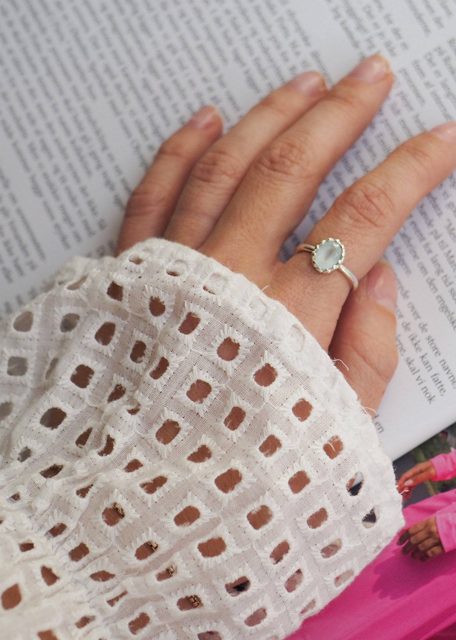 Woman with an elegant finger ring in sterling silver with a blue Aquamarine gemstone in a facet-cut and in a lace setting - perfect as the birthstone gift for her in march