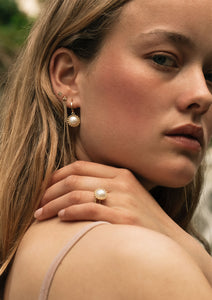 Woman wearing solid gold jewellery from carré with pearls. The pearls are of the mabe variety.