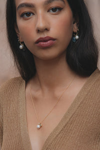 Woman with 10-karat gold jewellery from Carré Jewellery designed in Copenhagen and set with freshwater pearls and diamonds