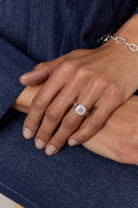 Man wearing a silver signét ring from Carré and a chunky silver bracelet.