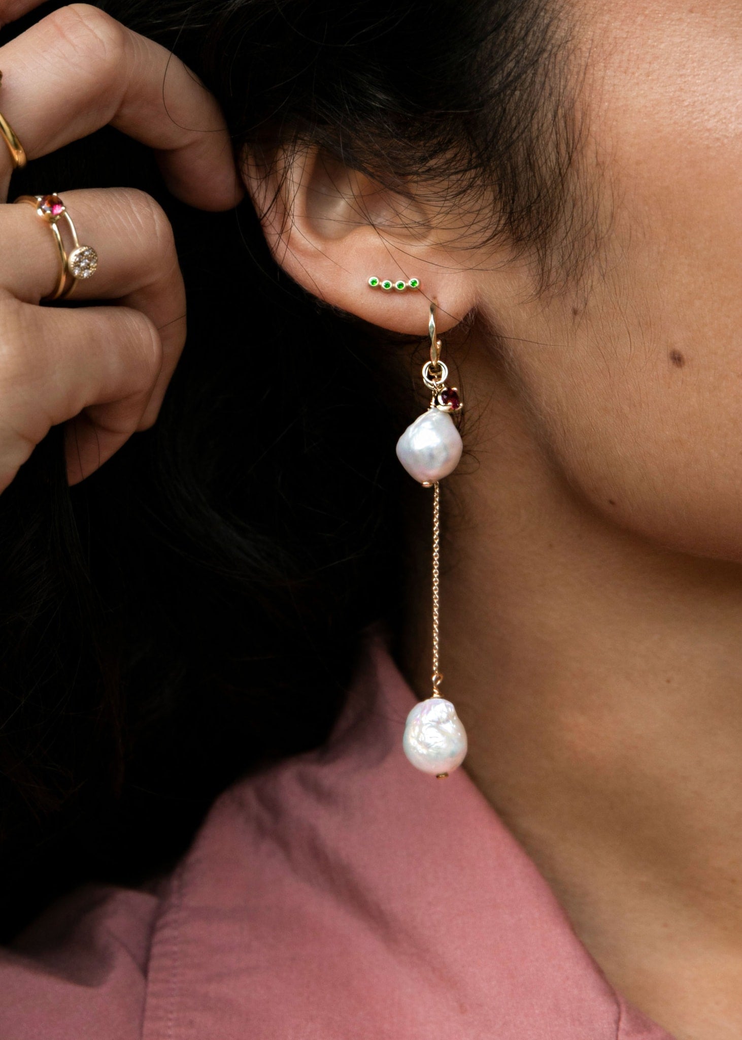 Woman wearing solid gold hoops and charms from carré jewellery set with pink tourmaline gemstones