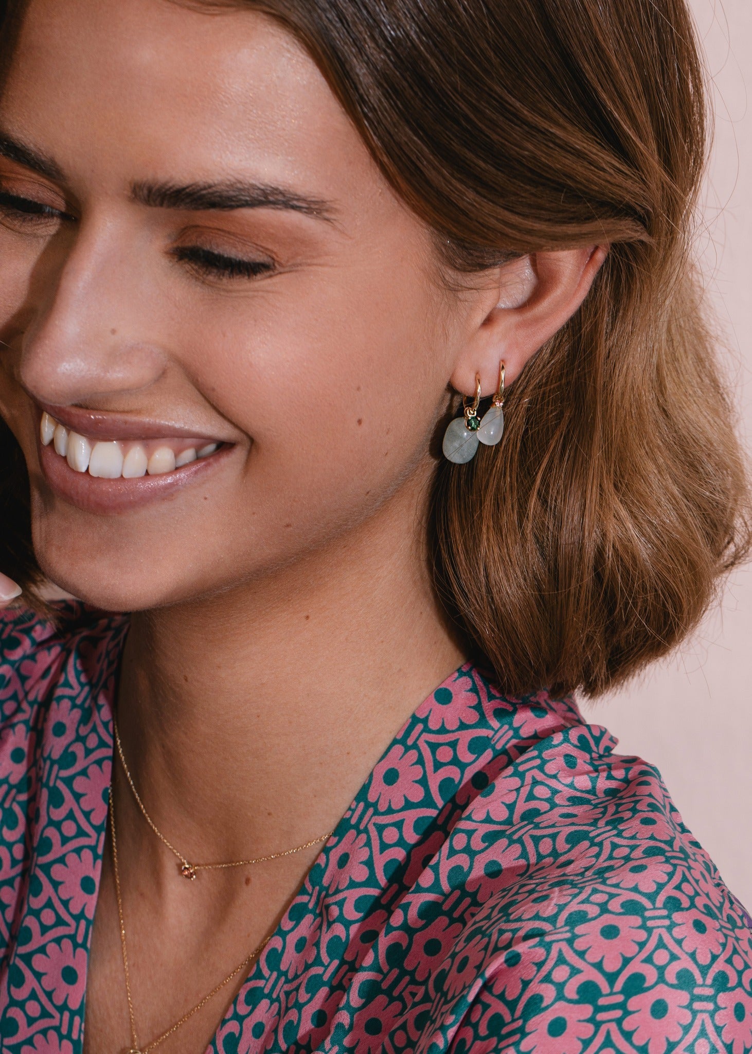 Smiling woman wearing solid gold jewellery from carré jewellery set with green tourmaline gemstones