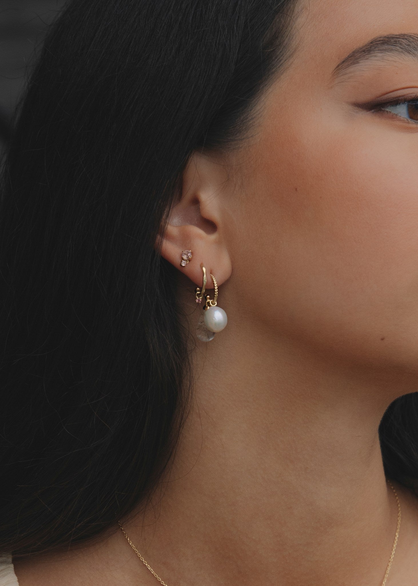 Woman wearing 10 karat solid gold hoops and charms from carré jewellery with pink tourmaline gemstones