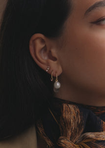 Woman wearing solid 10 karat gold hoops and charms from carré jewellery with pink tourmaline and freshwater pearls