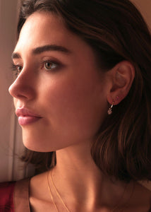 Woman with 10-karat earrings from carré jewellery with pink tourmalines and sand moonstone earrings in a heart shape