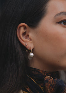 Woman with 10-karat gold earrings from Carré set with freshwater pearls, quartz and pink tourmaline gemstones.