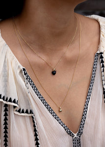 Woman wearing three heart pendants for necklaces in real gold from Carré Jewellery set with black agate, pink tourmaline and peridot gemstones