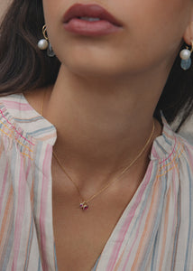 Woman wearing to gold heart pendants for necklaces from Carré Jewellery with  heart-shaped pink tourmaline gemstones