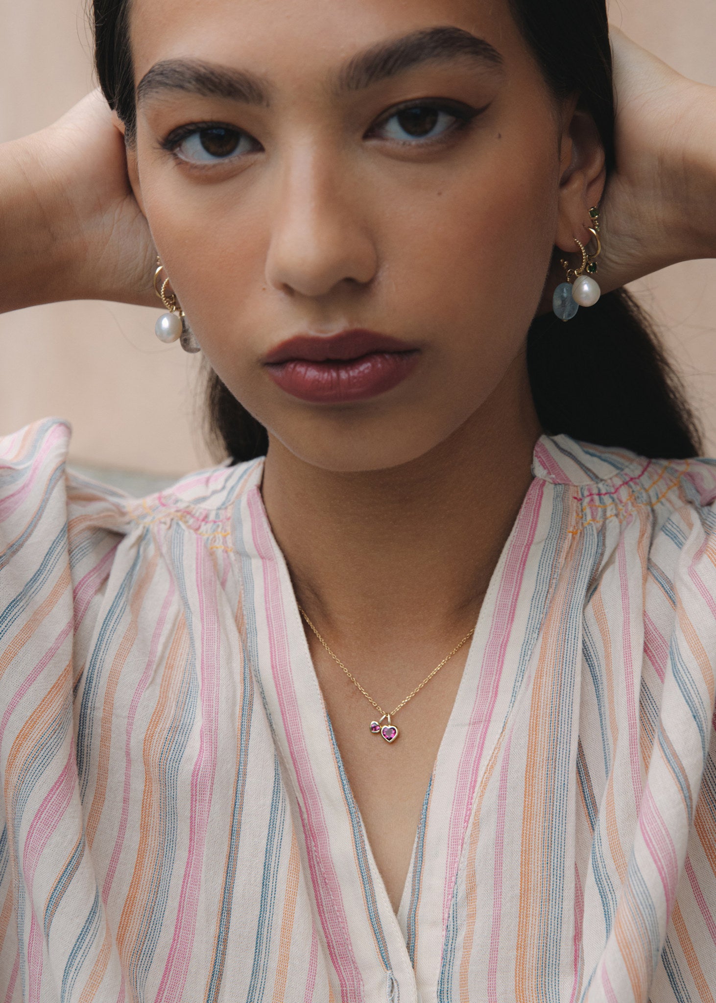 Woman wearing to gold heart pendants for necklaces from Carré Jewellery with  heart-shaped pink tourmaline gemstones