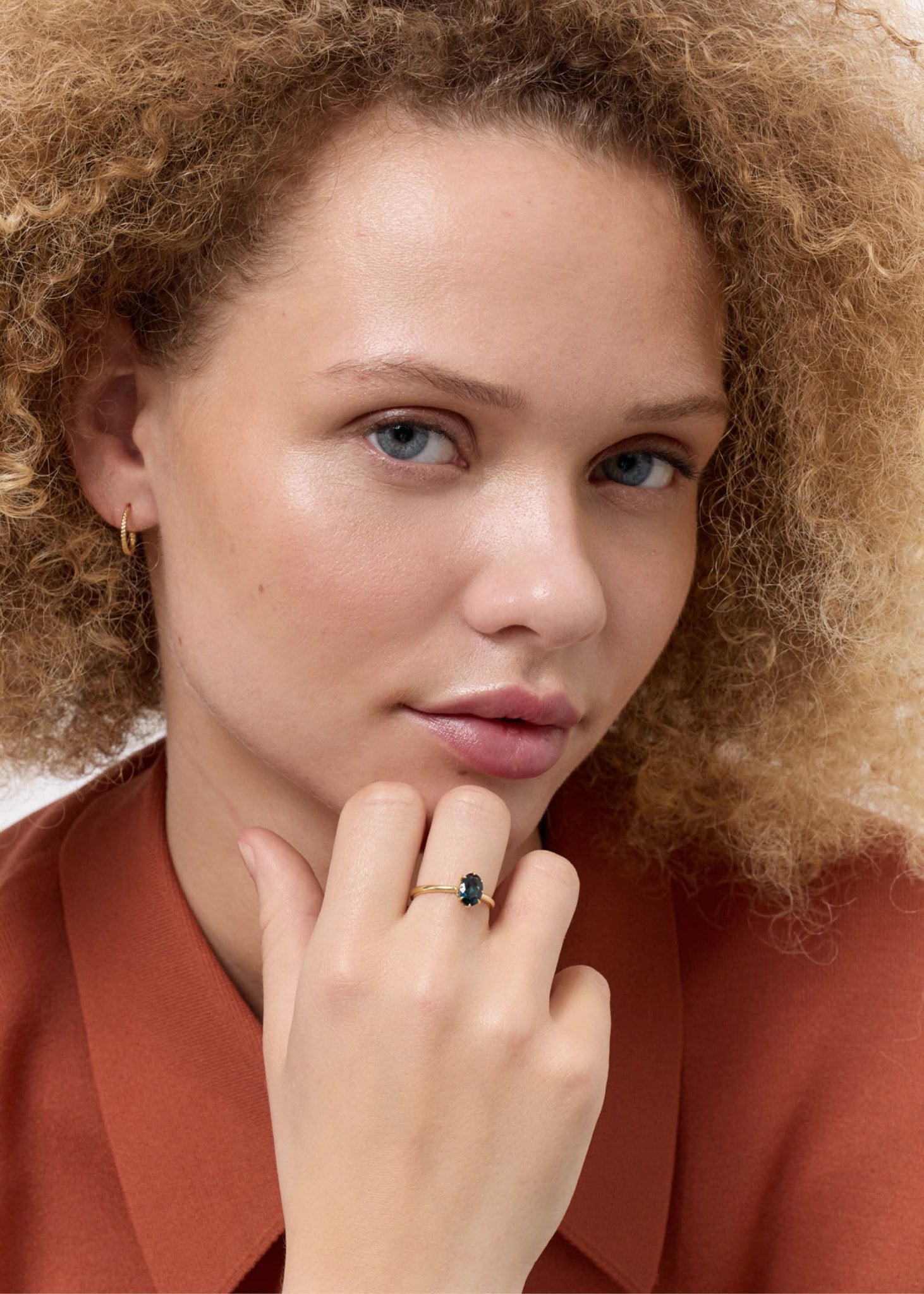 Kvinde med ring i ægte 10 karat guld med en london blå topas ædelsten i ovalslibning fra carré jewellery 