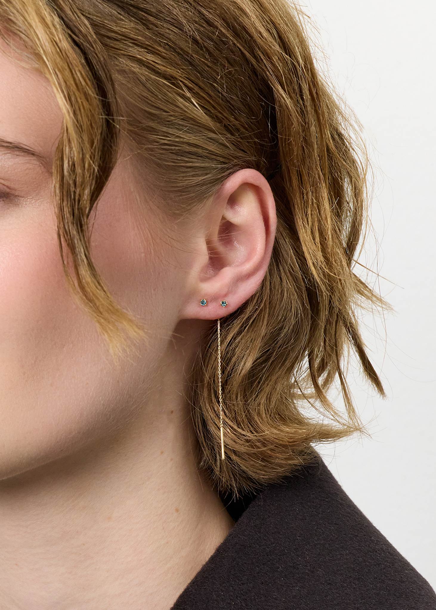 Ung kvinde med øreringe i 10-karat ægte guld fra carré jewellery med london blå topas ædelsten, der er novembers fødselssten