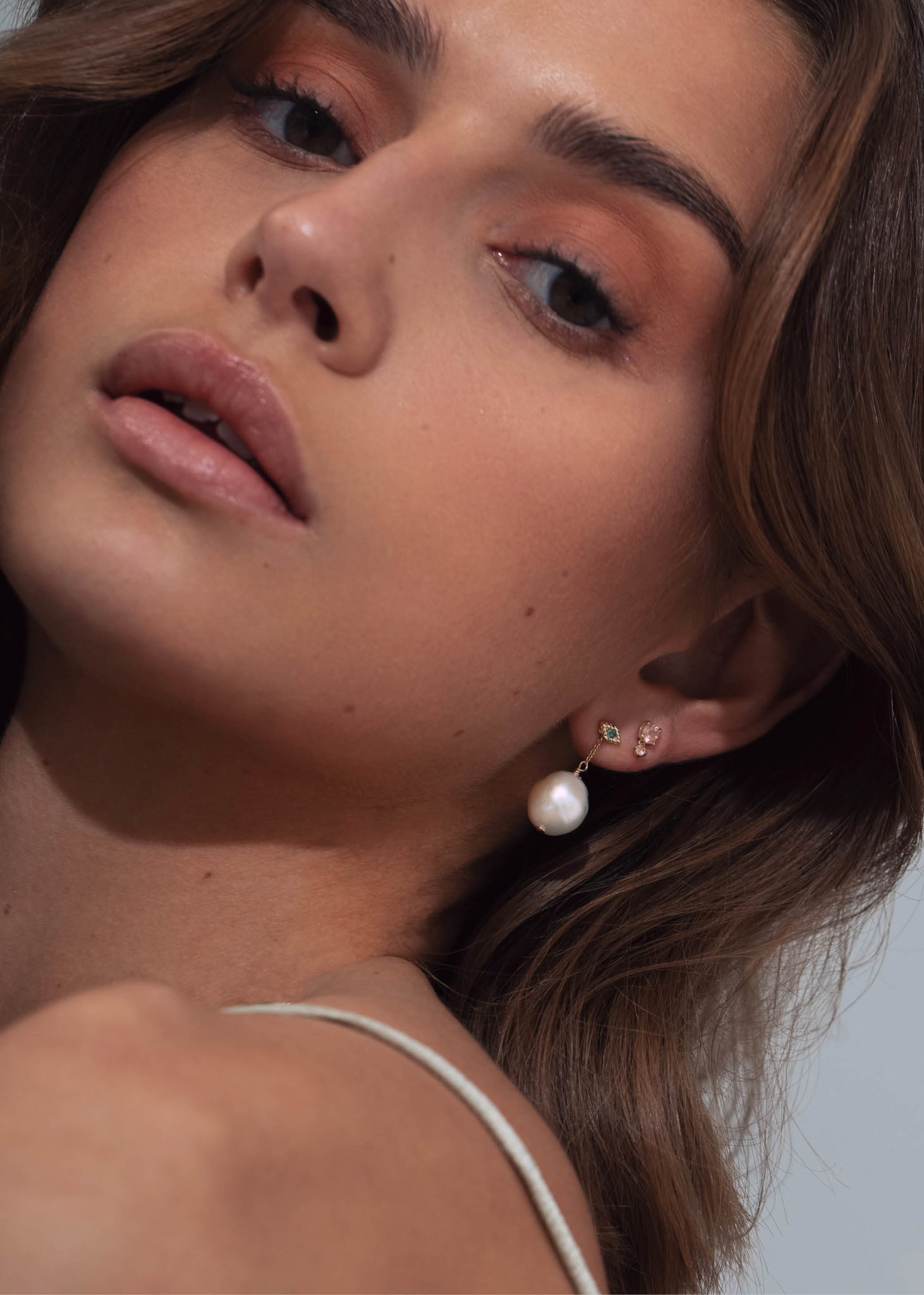 Ung kvinde med lille ørestik i 10k guld med en london blå topas ædelsten fra carré jewellery 