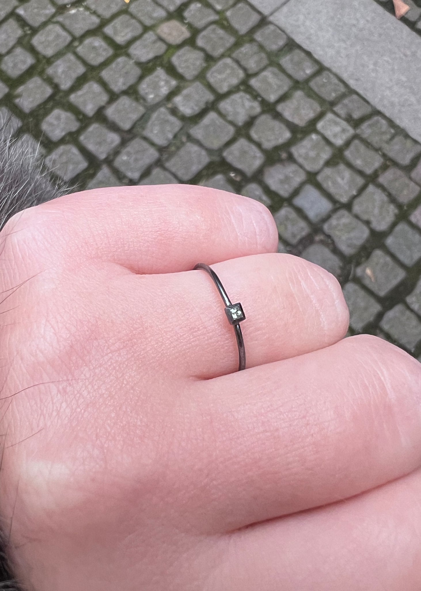 Woman wearing a black silver goth style ring with a real green sapphire gemstone from carré jewellery