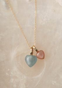 two solid gold heart pendants for necklaces from Carré. The pendants have a heart shaped aquamarine gemstone with a diamond and a heart shaped moonstone pendant with diamond