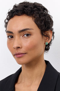 woman with a gold plated flower shaped earring from carré. The blue flower earring is set with amazonite gemstones and a prasiolite